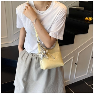 Détail du sac porté épaule jaune pâle avec pendentif étoile de mer argentée et cuir brillant