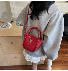 Détail du sac seau rouge vif à texture tressée avec serrure métallique et poignée