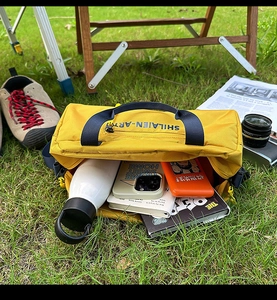 Detail of spacious yellow nylon crossbody bag interior with water bottle and books