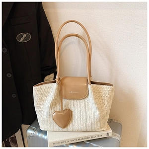 Detail of herringbone weave cream tote bag with leather handle and heart-shaped charm