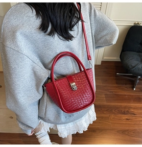 Détail d'un sac à main tressé rouge avec boucle en métal argenté et poignée ronde