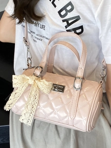 Pink quilted cylinder bag with cream lace bow and adjustable shoulder strap