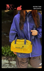 Detail of yellow nylon crossbody bag with SHILAIEN-AR logo and black webbing handles