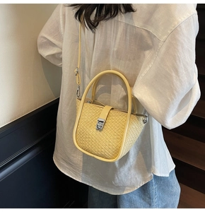 Détail du sac à main jaune clair à texture tissée avec fermoir rotatif argenté sur chemise