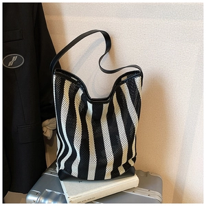 Detail of black and white striped mesh material with reinforced black leather straps on a bag