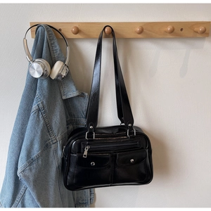 Detail of a vintage black leather bowling bag hanging on a rack with urban accessories