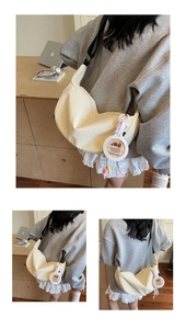 Détail d'un sac hobo demi-lune jaune crème avec un charm Capybara et une sangle
