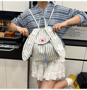 Detail of cute rabbit ear backpack flap with plush stars and striped canvas texture