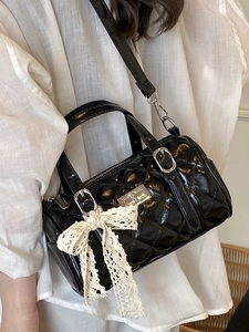 Minimalist black quilted cylinder crossbody bag with lace bow and metal twist lock