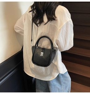 Détail du sac seau tissé noir avec serrure carrée argentée et texture en cuir élégant