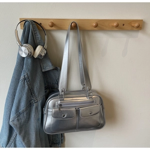 Silver metallic shoulder bag with utility pockets hanging with denim jacket and headphones
