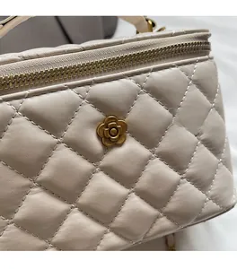 Close-up of beige quilted leather handbag featuring a golden camellia flower metal clasp