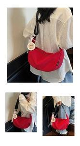 Détail du sac demi-lune en toile rouge avec bandoulière noire et breloque Capybara