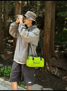 Close-up of neon green nylon crossbody bag with SHILAIEN-ART text in outdoor forest setting