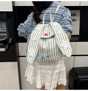 Detail view of rabbit ear backpack with green stripes and star patches on a female model