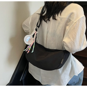 Gros plan du sac bandoulière croissant noir avec pendentif blanc et étiquette tissée