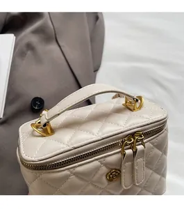 Detail of quilted leather bucket bag with top handle and golden flower charm