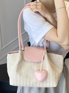 Pastoral woven straw tote bag with pink leather trim and heart charm for beach vacations