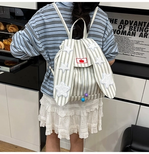 Detail of striped backpack with rabbit ears and star patches shown in lifestyle scene