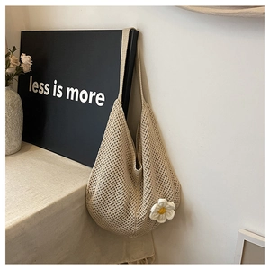 Détail d'un sac cabas tissé beige avec une fleur en tricot 3D blanche au décor minimaliste
