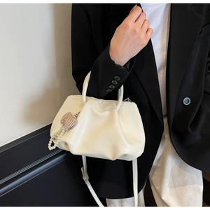 Detail of cream cloud pleated handbag with rigid handles and a stylish pearl charm