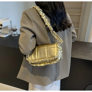 Détail du sac doré matelassé avec bordures plissées et finition en similicuir métallisé