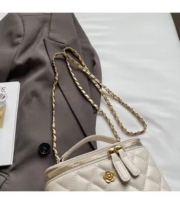 Detail of quilted texture with golden camellia flower and chain strap on stylish handbag