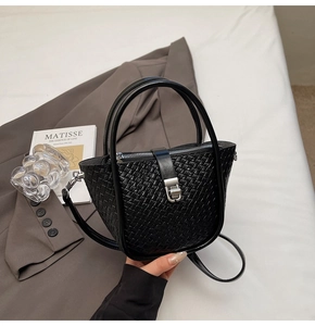 Vue détaillée de la texture tressée noire du sac seau avec boucle en métal argenté