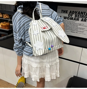 Detail of cute rabbit-ear design on a green and white striped canvas backpack for women