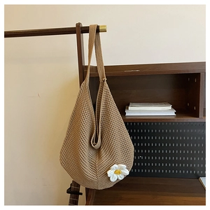 Détail du sac cabas au crochet avec marguerite 3D blanche sur un support en bois rustique