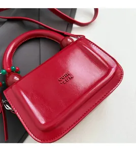 Dettaglio della borsa in pelle cerata rossa con logo COTH 2DN sbalzato e perline decorative