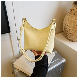 Détail du sac croissant jaune clair avec texture froissée et bandoulière à nœuds