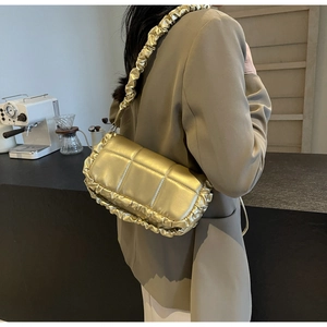 Détail d'un sac à main matelassé doré champagne avec bords à volants dans un café