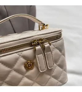Close-up of golden floral hardware and dual metal zippers on quilted handbag