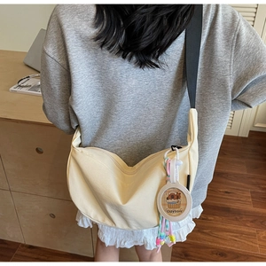 Détail d'un grand sac bandoulière en toile beige avec sangle réglable et pendentif capybara