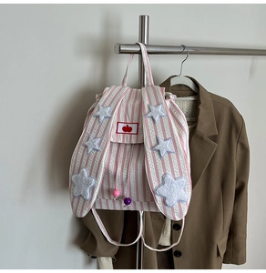 Detail of pink striped canvas backpack with long rabbit ears and white plush stars decoration
