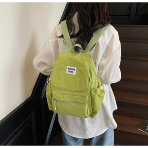 Detail view of mint green nylon backpack with drawstring pockets shown on a model