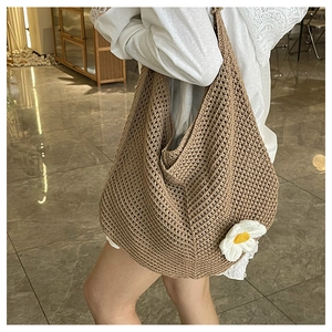 Détail du sac hobo en crochet avec une fleur de soleil blanche et une texture en tricot creux