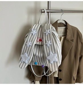 Close-up of cute rabbit ears with star patches and cherry detail on beige striped backpack