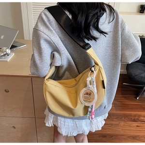 Détail du sac bandoulière en nylon jaune avec breloque capybara et sangle large réglable