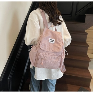 Detail view of pink nylon backpack showing drawstring side pocket and flip cover