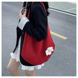 Détail d'un sac cabas rouge tricoté main avec un pendentif floral 3D blanc élégant