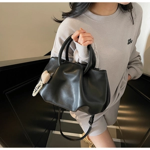 Detail of black pleated cloud bag with pearl heart charm and soft PU leather texture