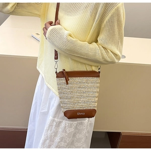 Detailansicht der Stroh-Eimertasche mit braunem Lederboden und Markenlogo