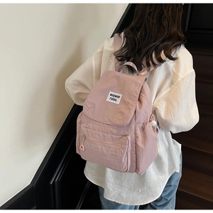 Detail of light pink drawstring backpack with woven brand label and front zipper pocket