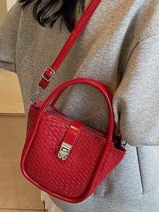 Sac seau rouge vif avec texture tissée et boucle argentée, porté à l'épaule