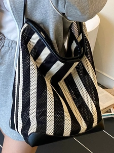 Fashionable black and white striped hollow mesh tote bag for women shown on model shoulder