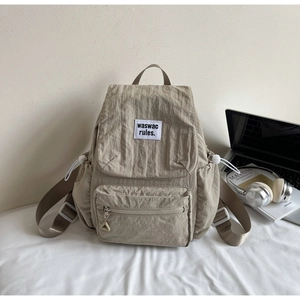 Detail of light khaki nylon backpack with drawstring pockets and minimalist logo
