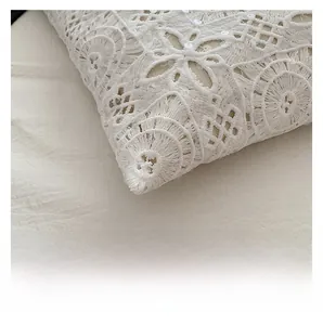 Dettaglio del pizzo bianco ricamato con paillettes e rifiniture delle cuciture