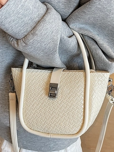 Sac seau tissé beige minimaliste pour femme porté à l'épaule par un mannequin